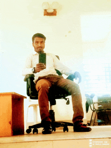 a man sitting in an office chair taking a selfie with a symphony z28 triple camera