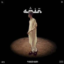 a man in a white robe is standing in a dark room on the cover of an album