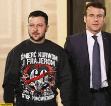 two men are standing next to each other and one has a shirt that says śmierc kurwom i frajerom