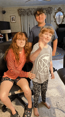 a boy and two girls are posing for a picture with one girl wearing a nyc shirt