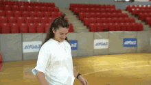 a woman in a white shirt is standing on a basketball court in front of a wall that says aygaz