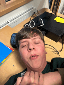 a boy laying on a desk with his eyes closed and a pencil case that says 00 on it