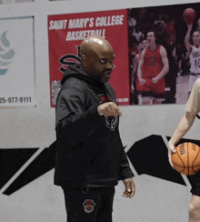 a man stands in front of a saint mary 's college basketball poster