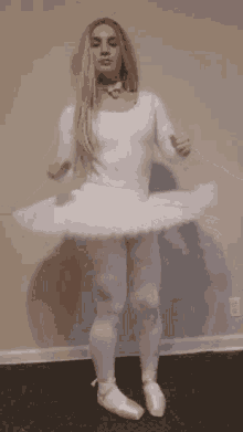 a woman in a white tutu and pointe shoes is dancing in a room .