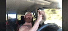 a shirtless bearded man is driving a car with a white hat on