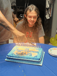 a man wearing a nebraska university shirt cuts a birthday cake