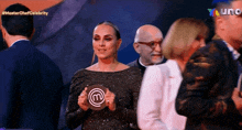 a woman in a black dress is holding a master chef celebrity plaque