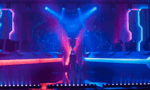 a stage with blue and purple lights and a person standing in front of it