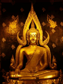 a gold statue of a buddha sitting in front of a black background