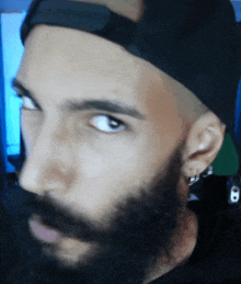 a man with a beard wearing a hat and earrings