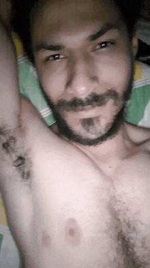 a man with a beard is laying on a bed with his shirt off