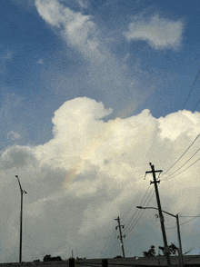 a rainbow is visible in the clouds above a telephone pole