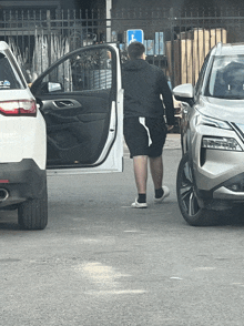 a man getting out of a white car with a nissan logo on the back of it