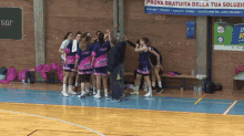 a group of female basketball players huddle on the court in front of an ad for prova gratuita della tua soluzio