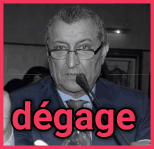 a man in a suit and tie is speaking into a microphone and the word degage is on the bottom