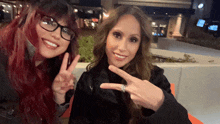 two women are posing for a picture and one of them is wearing a ring on her finger