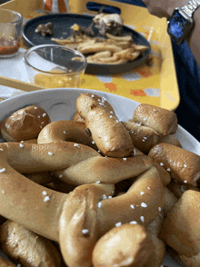 a plate of pretzels sits on a table next to a tray of french fries