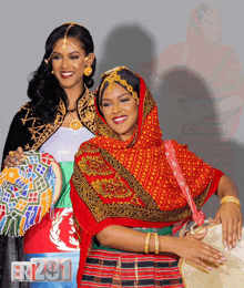 a woman in a red scarf is holding a drum next to a woman in a black jacket