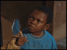 a young boy in a blue shirt is holding a stuffed animal in his hand .