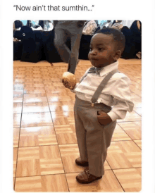 a little boy in a tuxedo is holding a piece of bread in his hand