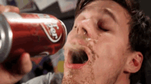 a man drinks a can of dr pepper from his mouth