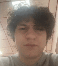 a young man with curly hair is taking a selfie with a ceiling in the background .