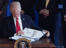 a man in a suit and tie is signing a document with the seal of the president of the united states on it