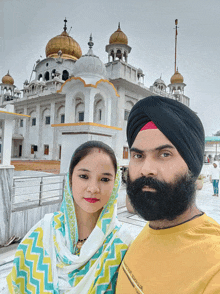 a man and a woman pose for a picture in front of a building that has a dome on top