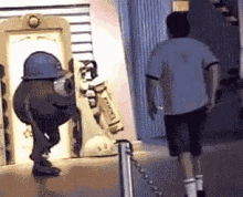 a man in a white shirt is walking away from a man in a blue helmet .