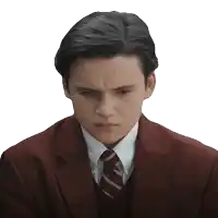 a young man wearing a suit and tie looks down