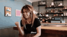 a woman is sitting at a bar and says bien