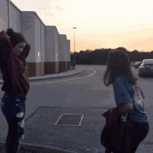 two girls are standing in front of a building and one is wearing a shirt that says ' a ' on it