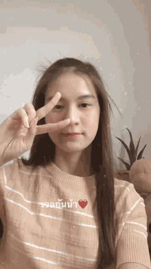 a girl giving a peace sign with a heart next to her