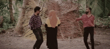 a woman in a hijab is dancing with two men in plaid shirts .