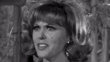a black and white photo of a woman wearing earrings and a wig .