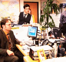 a man in a suit sits at a desk in front of a computer with a sign that says ' office ' on it