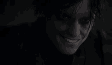 a close up of a person 's face in a dark room smiling .