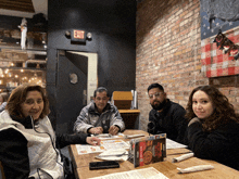 a group of people are sitting at a table with an exit sign above them