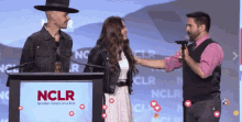 a man speaking into a microphone next to a woman and a sign that says nclr national council of la race