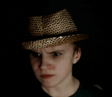 a young man wearing a hat with a black band