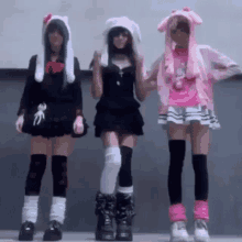 a group of three girls are standing next to each other wearing bunny hats .