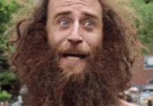 a man with a beard and curly hair is making a funny face .