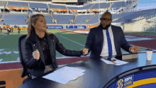 a man and a woman are sitting at a desk with espn network written on the bottom of the table