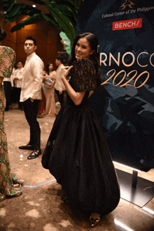 a woman in a black dress is standing in front of a sign that says rnoc2020