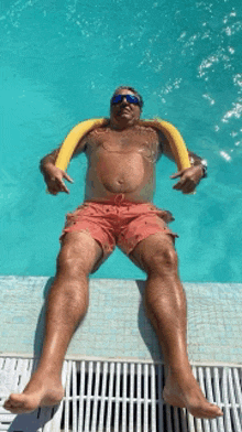 a man is laying on the edge of a swimming pool with a yellow float around his neck