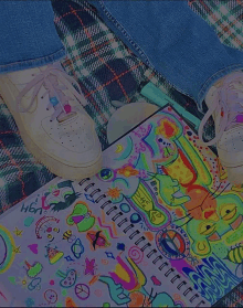 a person is laying on a plaid blanket with their feet on a colorful notebook that says h6n