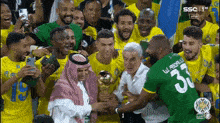 a group of soccer players are posing for a picture with a man holding a trophy with the number 32 on his jersey