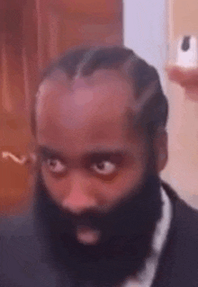 a man with a beard and braids is wearing a suit and tie and looking at the camera .