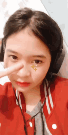 a girl wearing headphones and a red jacket has a star on her face
