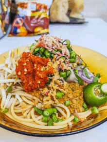 a close up of a plate of noodles with vegetables and sauce